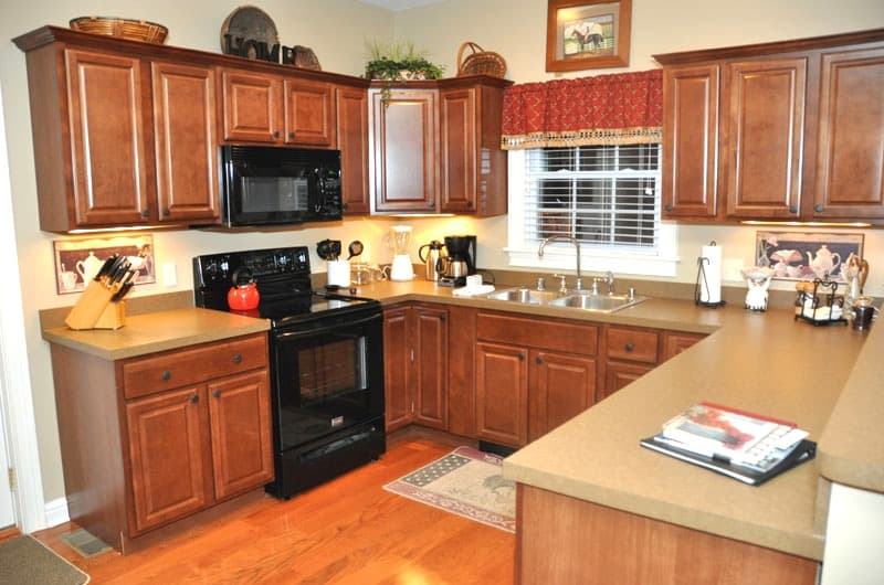 A cozy kitchen featuring dark wood cabinets, black appliances, and a well-organized countertop.
