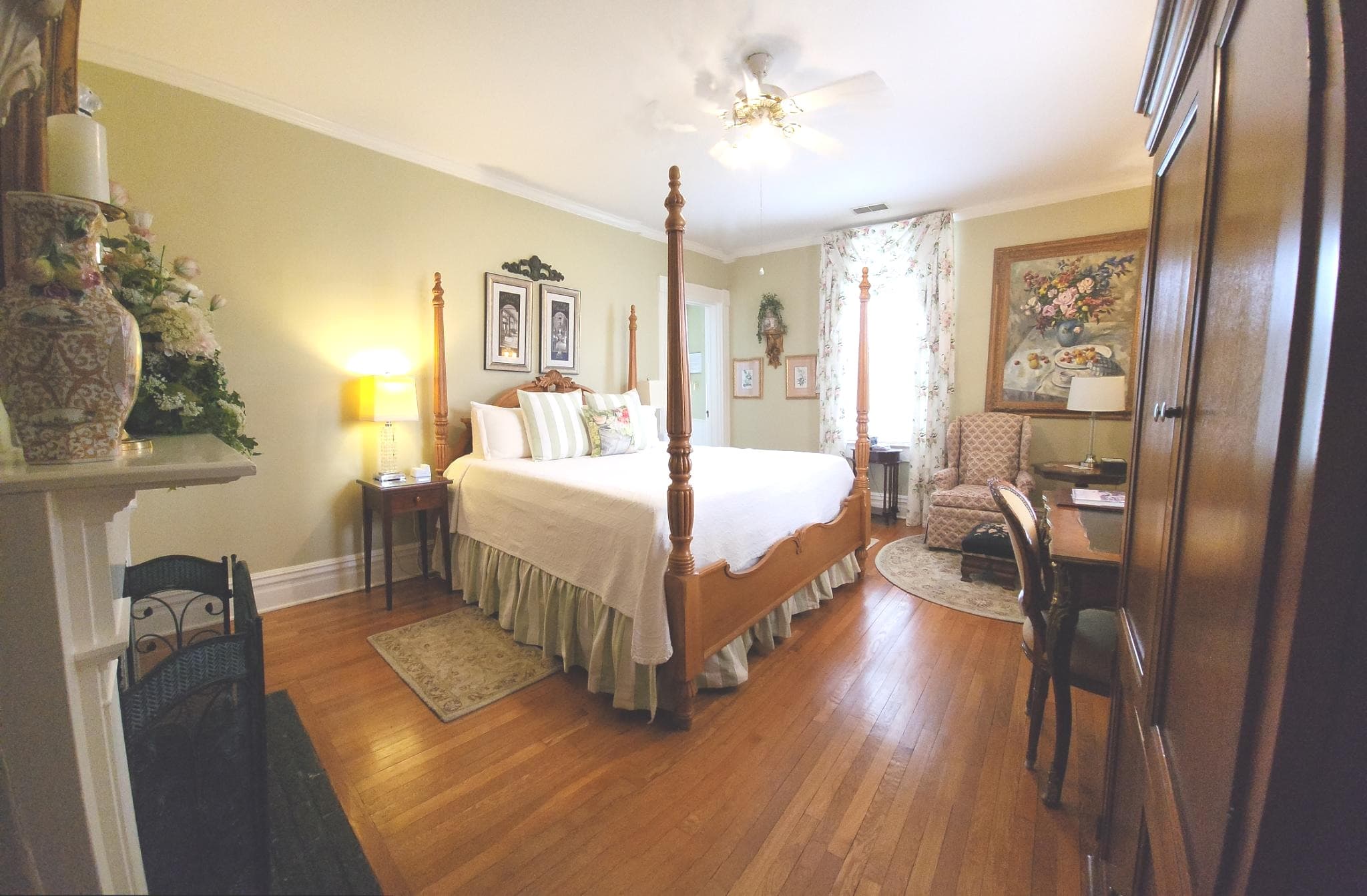 A cozy, well-decorated bedroom featuring a four-poster bed, armchair, and wooden furnishings.