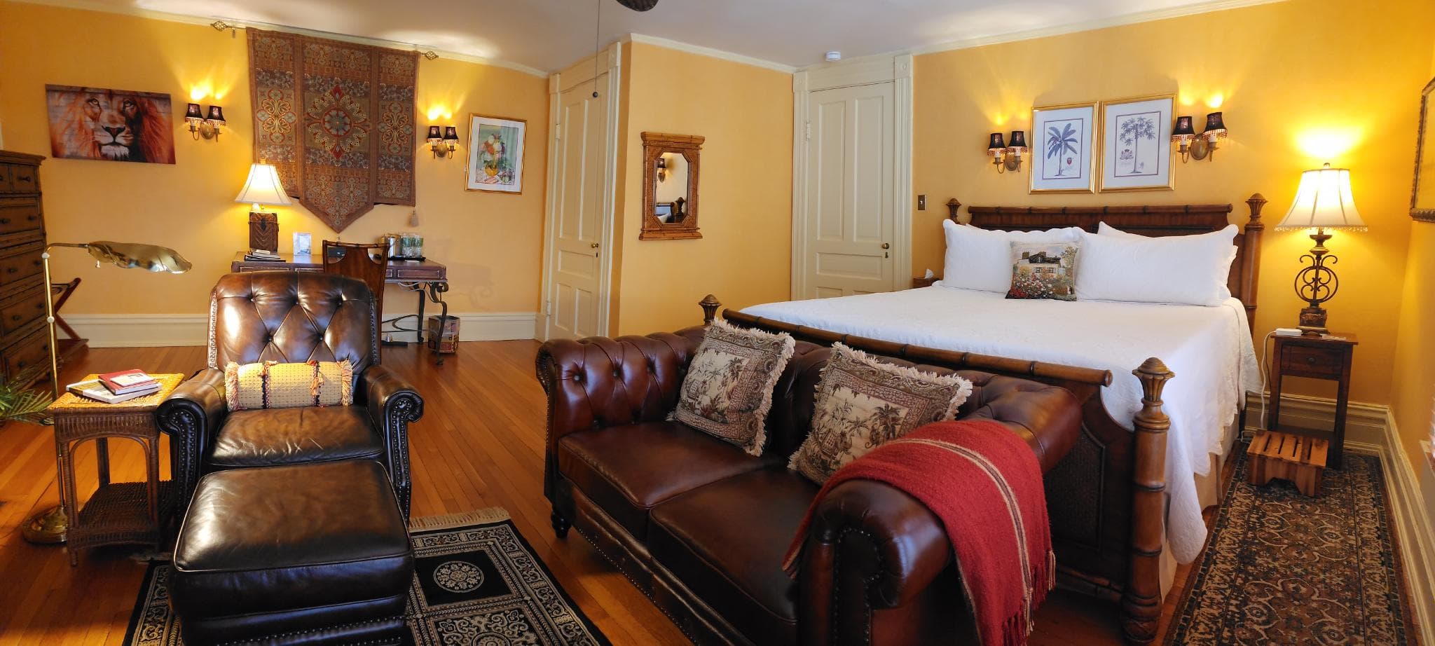 A cozy bedroom featuring a king-sized bed, leather seating, and warm, inviting decor.