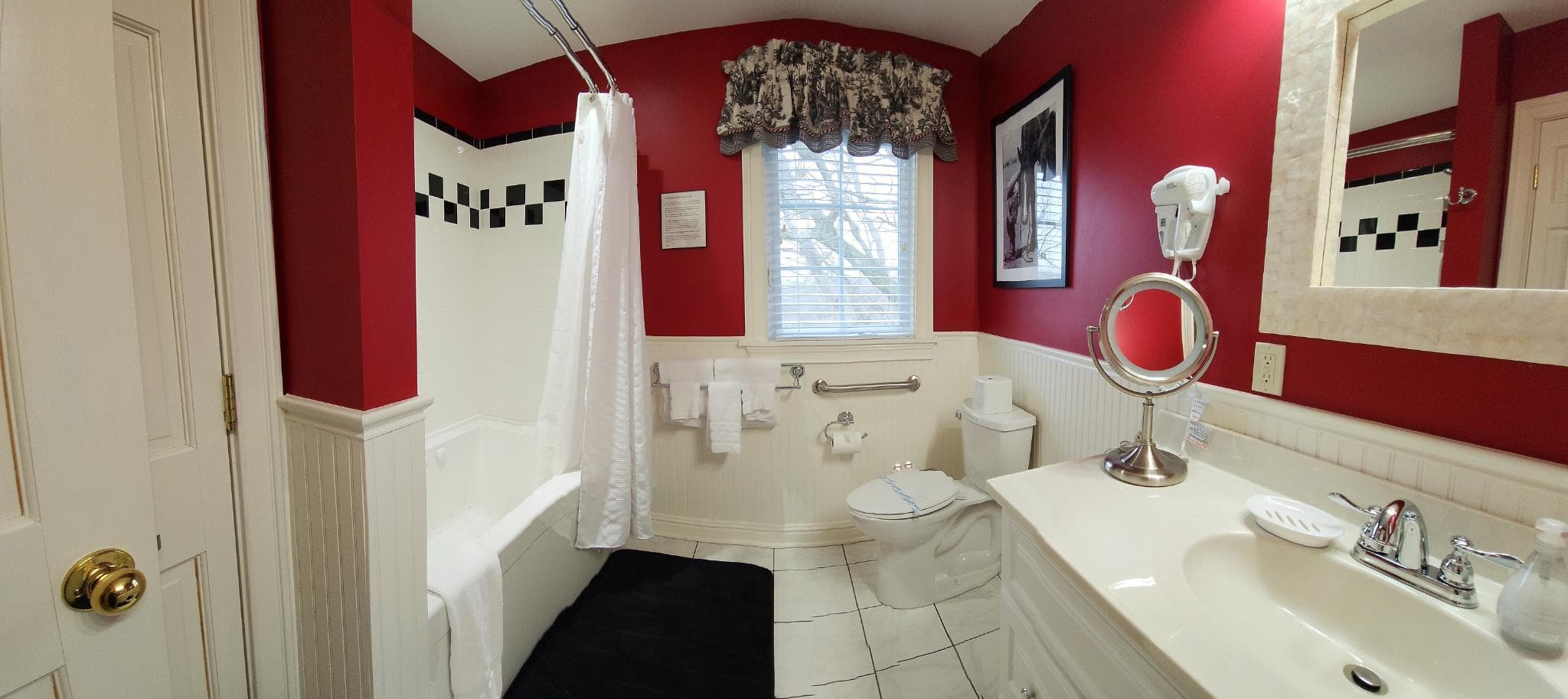 A colorful bathroom with red walls, a shower curtain, and a white vanity.