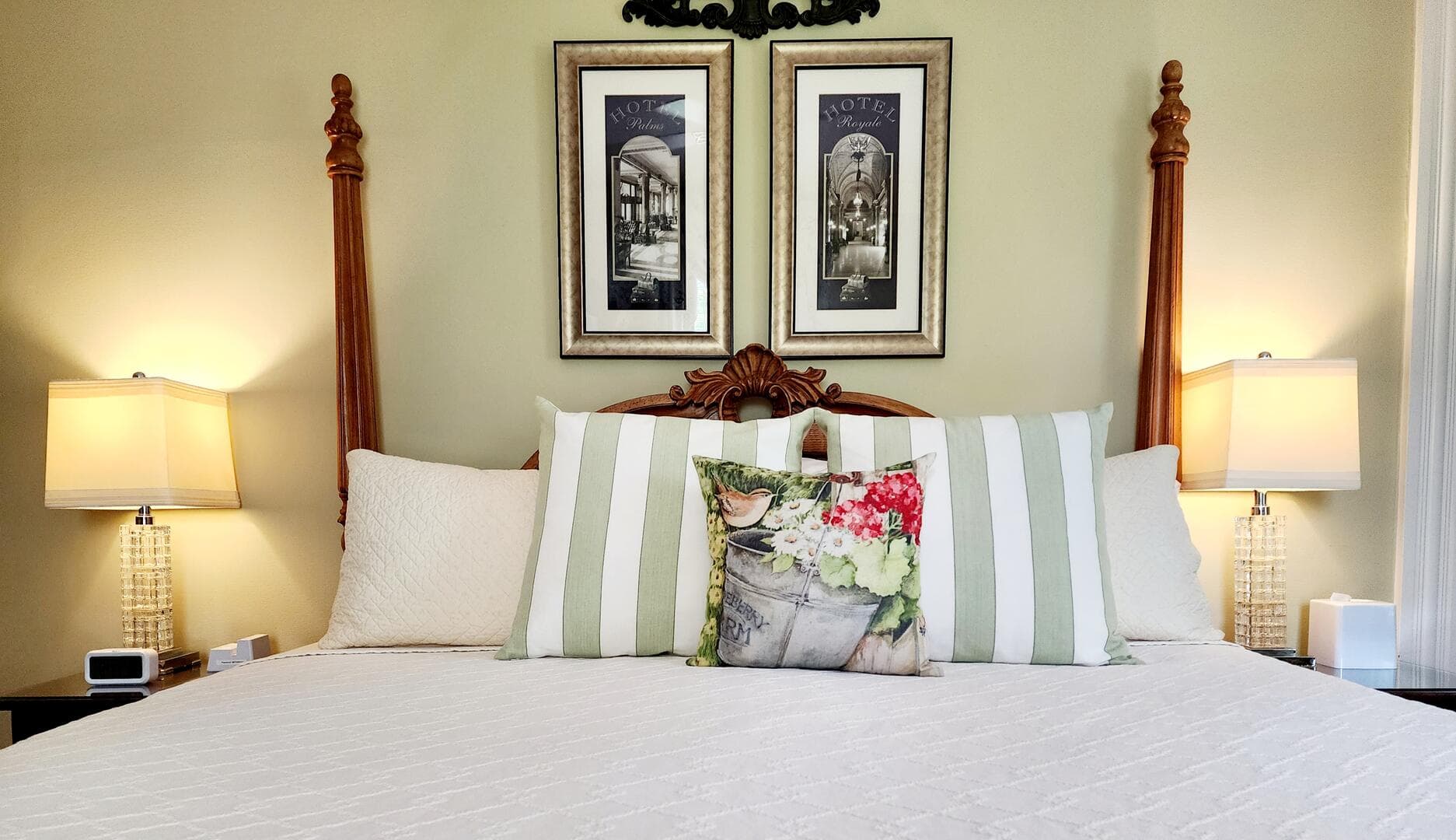 A neatly made bed with striped pillows, decorative cushions, and framed artwork on the wall.