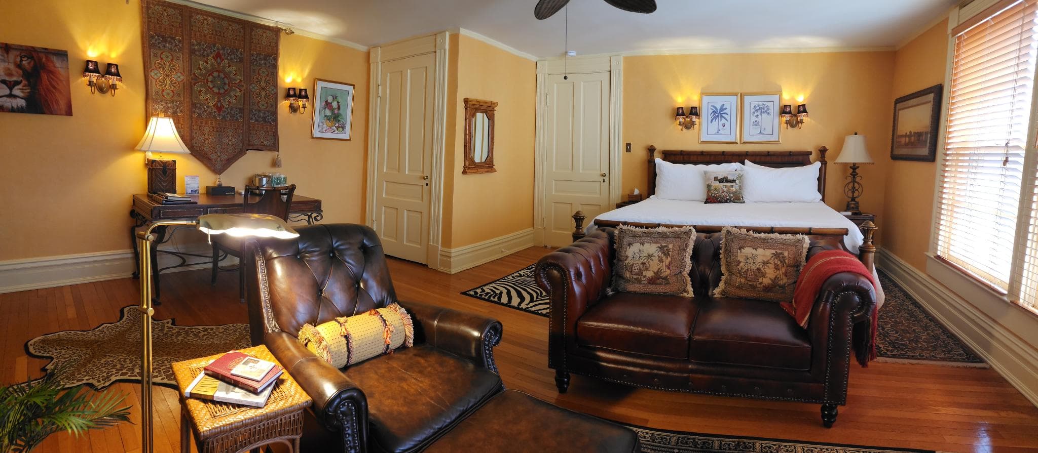 Cozy bedroom with a queen bed, leather seating area, and warm yellow walls.