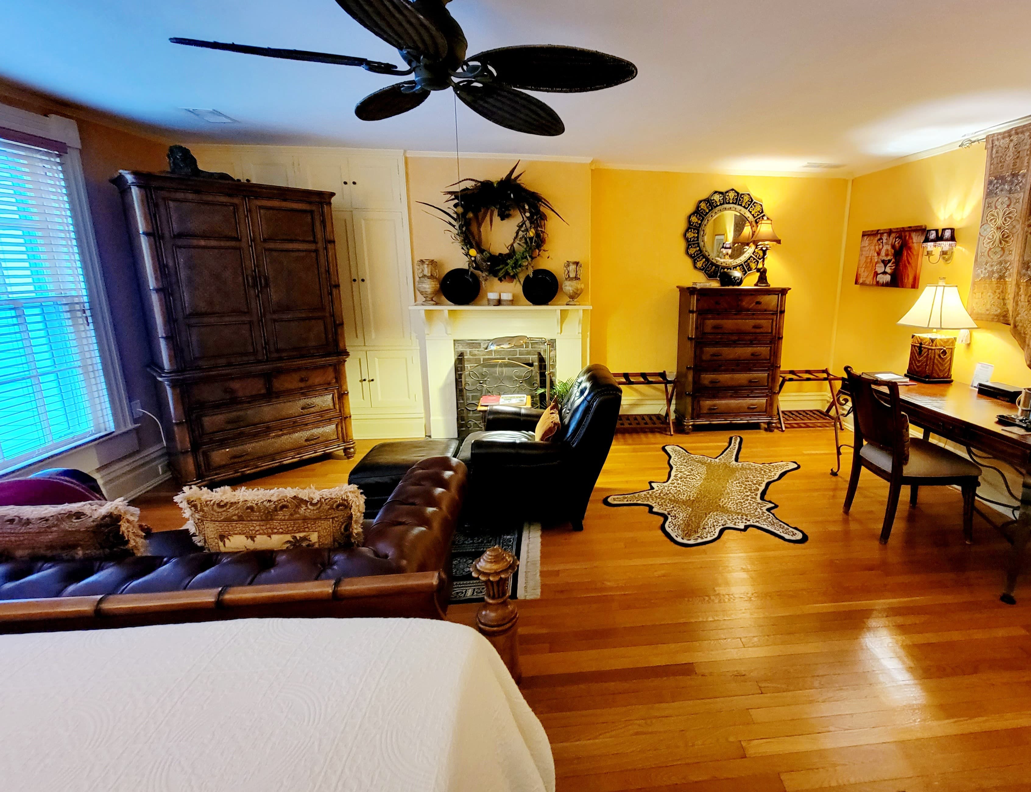 Cozy bedroom with wooden furniture, a fireplace, and warm yellow walls.
