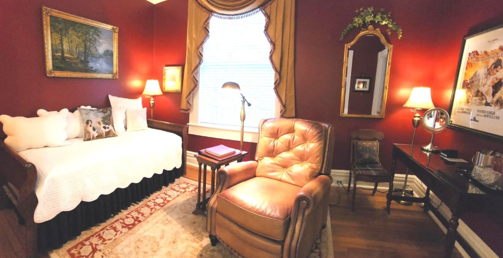 Cozy room featuring a daybed, leather armchair, and warm red walls with decorative accents.