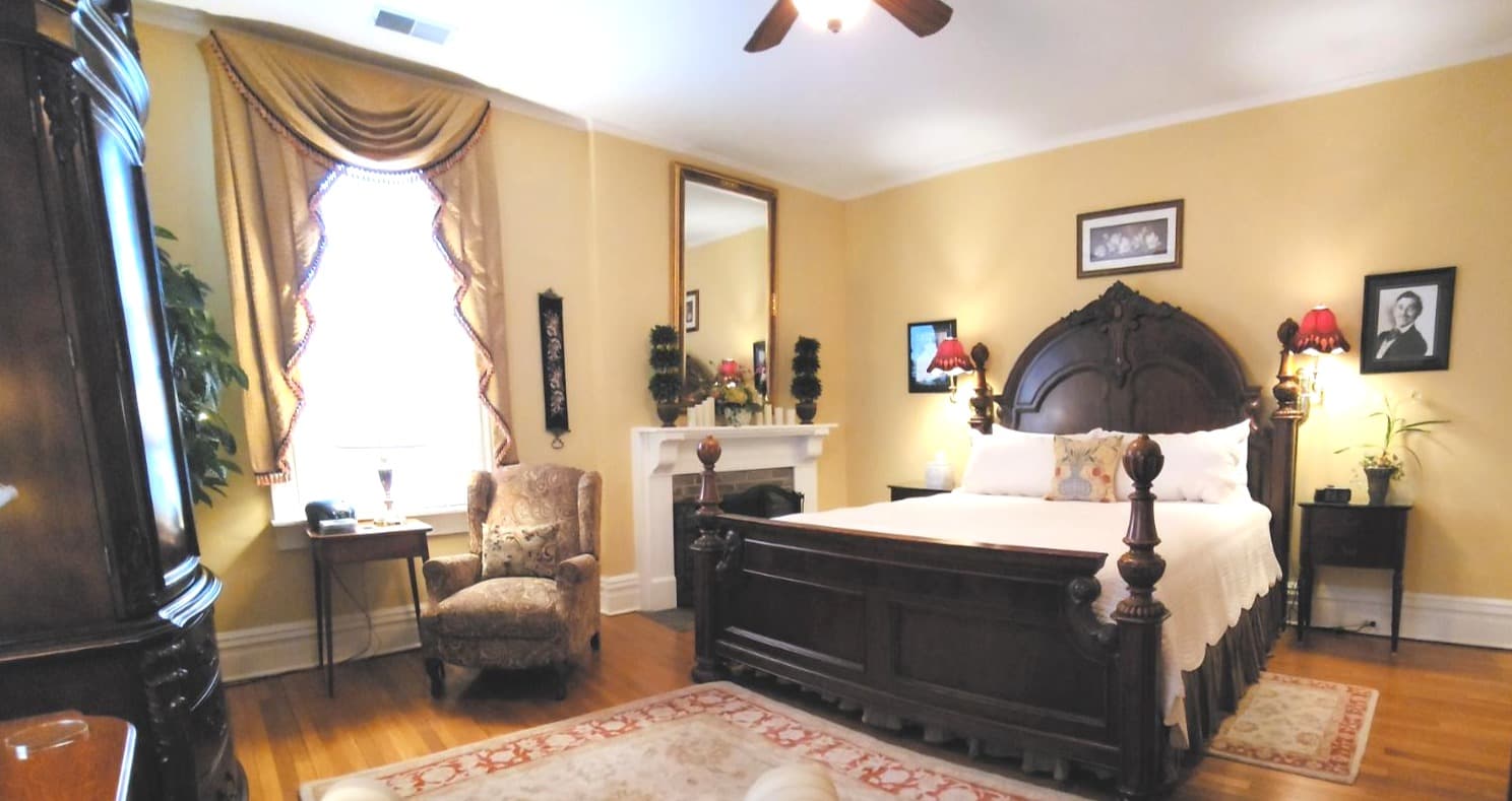 A cozy bedroom featuring a wooden bed, armchair, and decorative wall art.