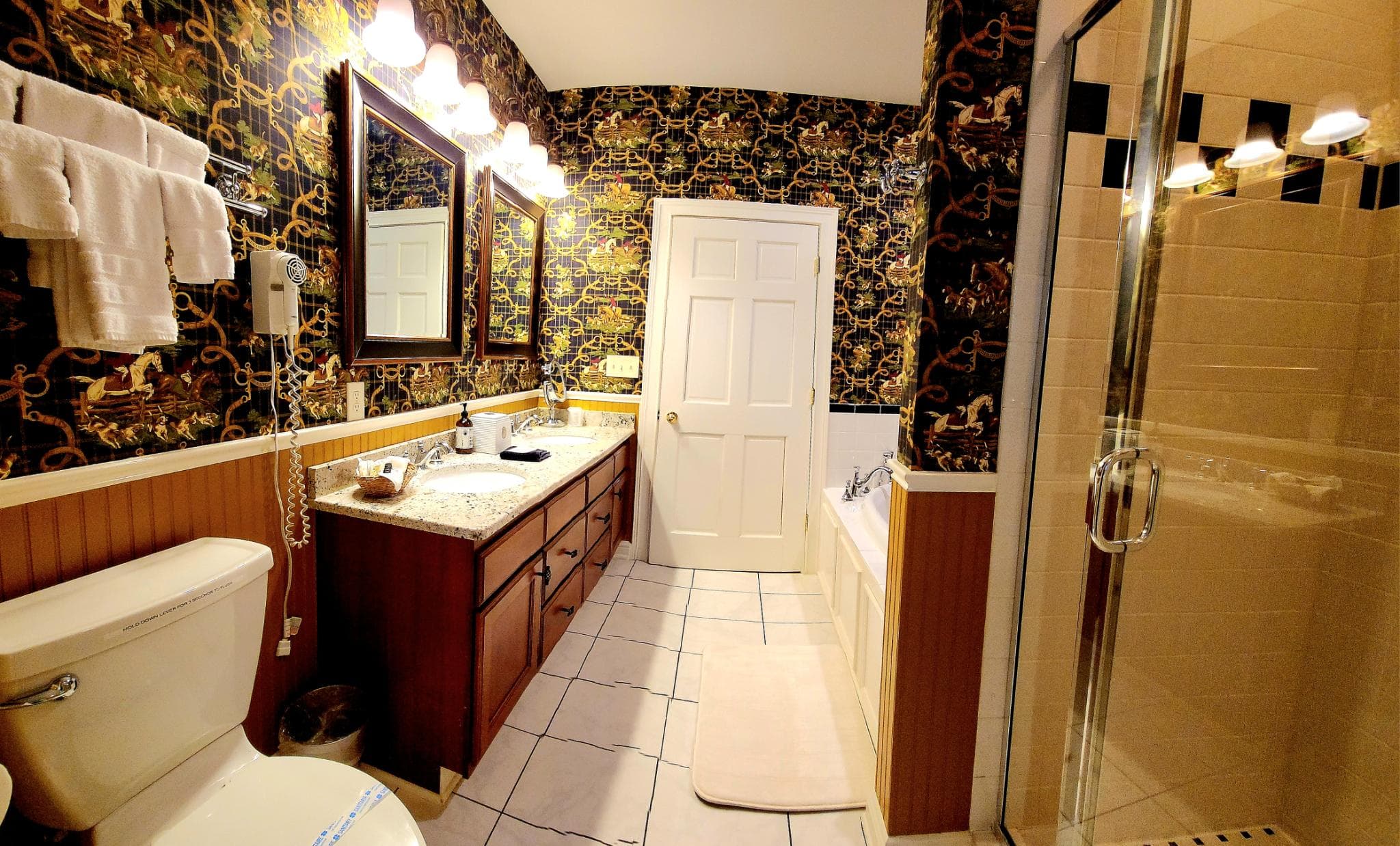 A stylish bathroom featuring a double vanity, shower, and bathtub with patterned wallpaper.