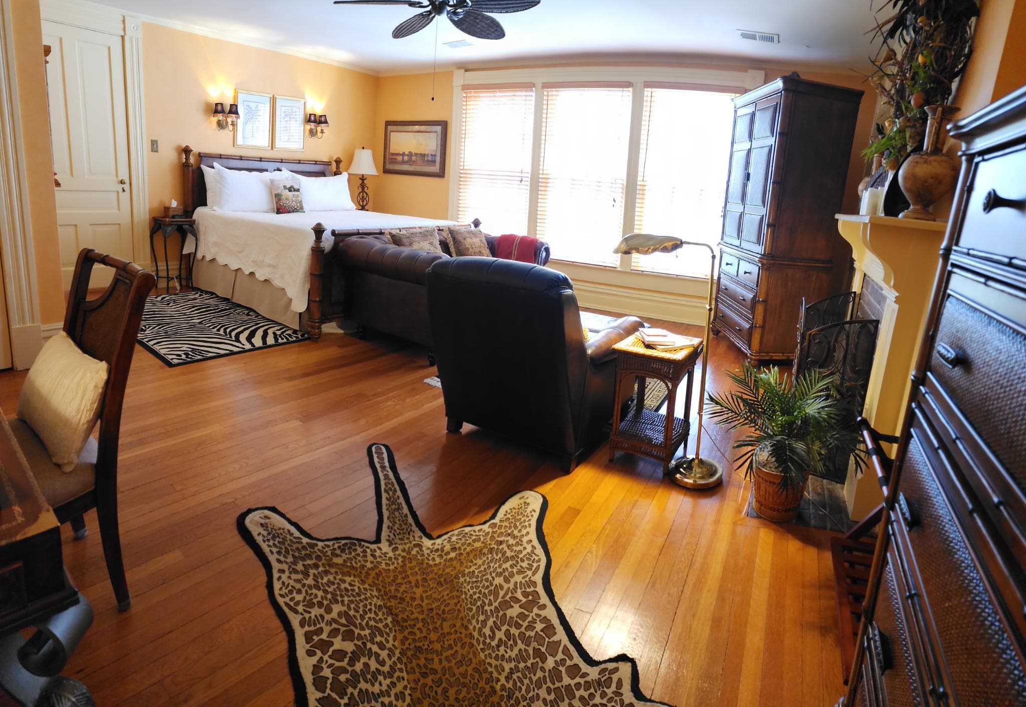 A cozy bedroom with a bed, seating area, wooden furniture, and decorative rugs.