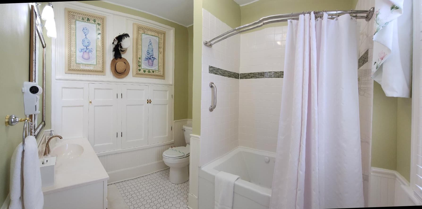 A bright, vintage-style bathroom featuring a bathtub, shower curtain, and white cabinetry.