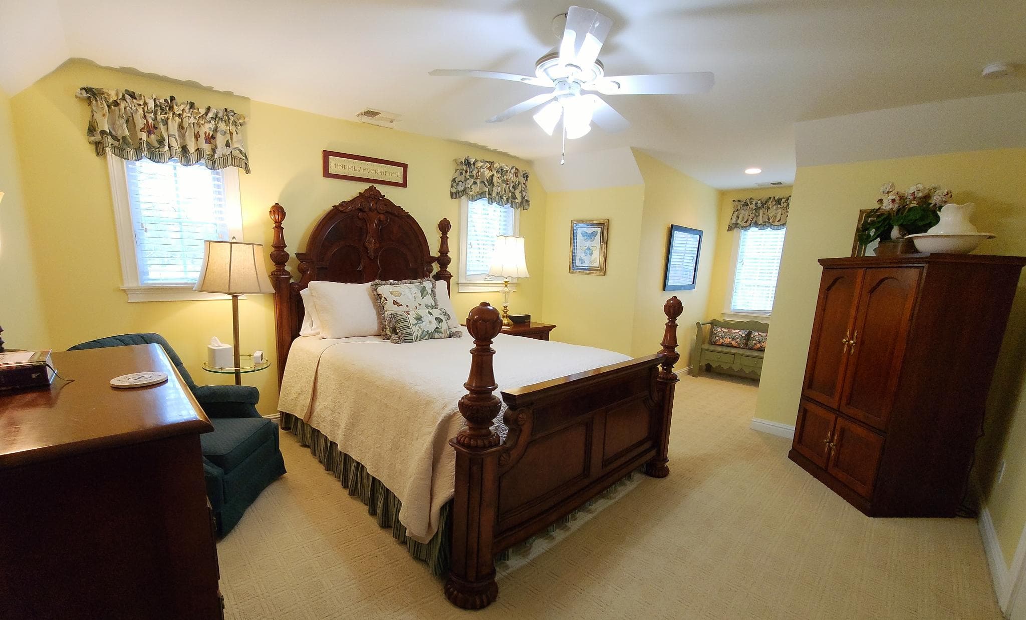 Bright and cozy bedroom with a wooden bed, green armchair, and decorative windows.