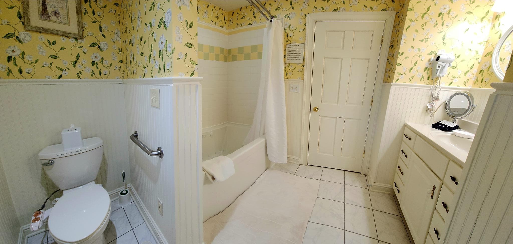 A well-decorated bathroom featuring a toilet, bathtub with a shower curtain, and a vanity with a mirror.